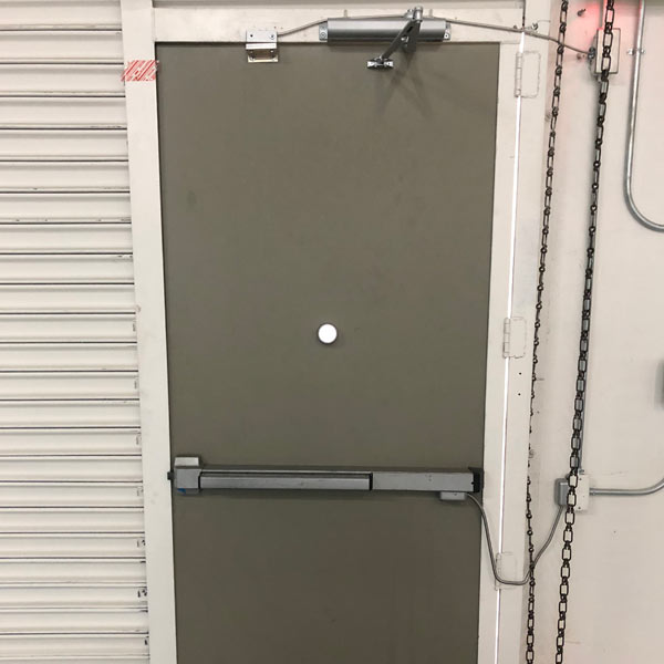 Commercial back of house door with closer, push bar, and additional security features installed in an industrial property