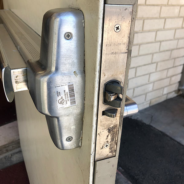 Closeup photo of door push bar and other hardware installed for an exterior entrance
