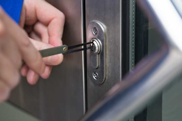 Commercial locksmith picking a cylinder lock on an aluminum glass door