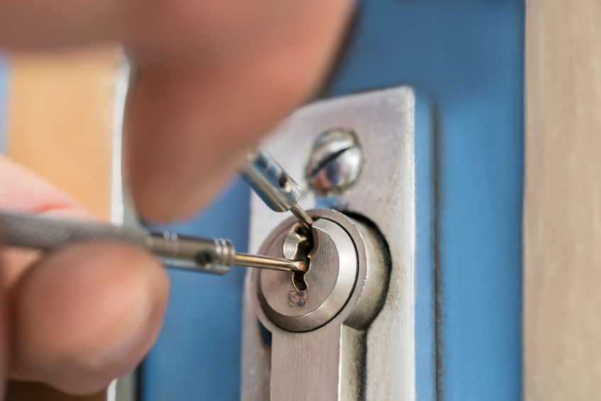commercial locksmith picking lock on the exterior door of a building in danville